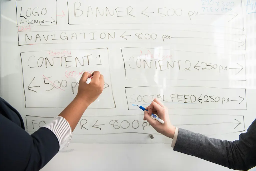 Zwei Personen analysieren gemeinsam Content auf einer Tafel, um relevante Stellen für die Integration von Backlinks zu markieren.